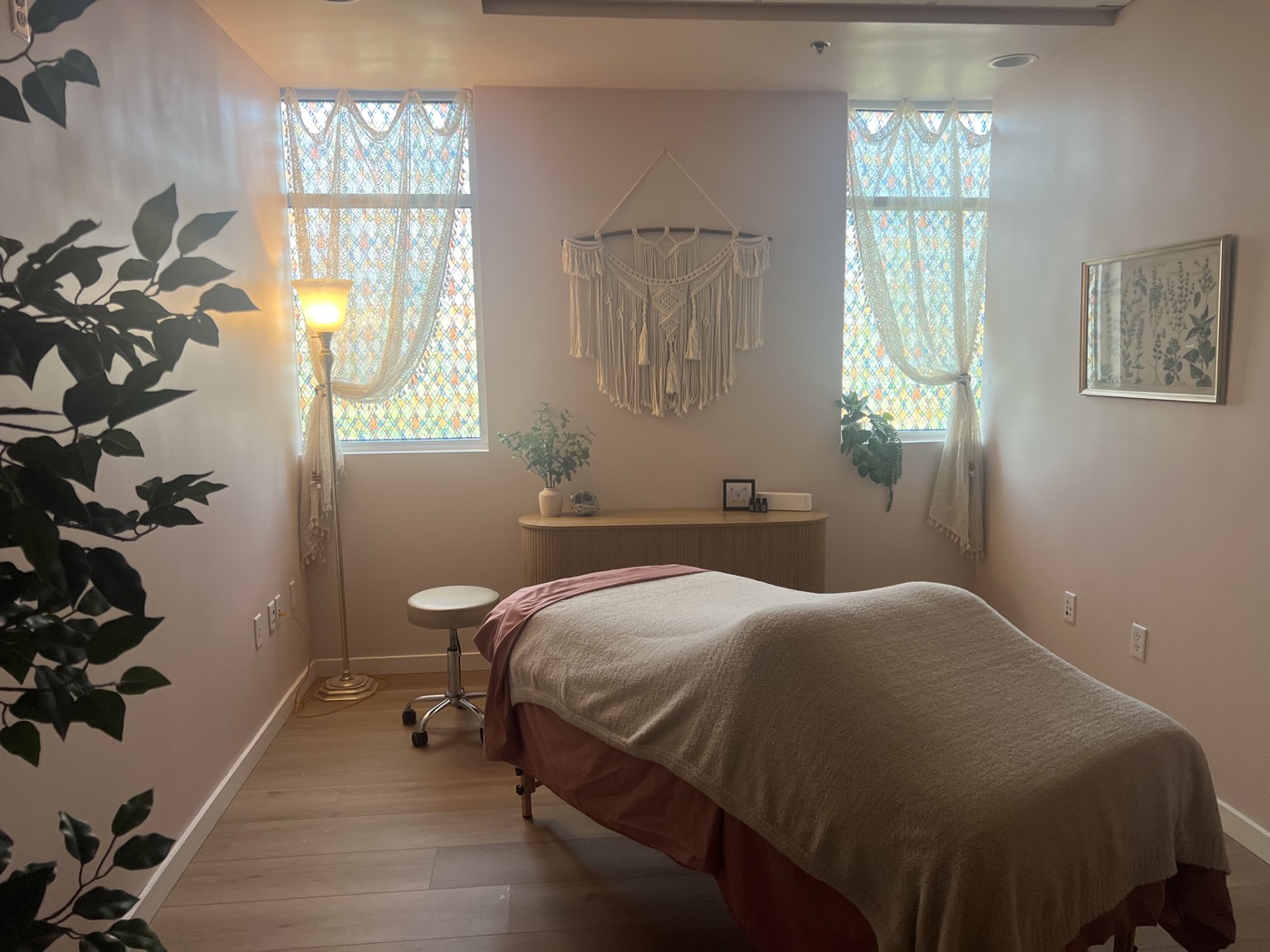 Max's studio: a draped massage table, warm lamp light and macramé between two lace-curtained windows